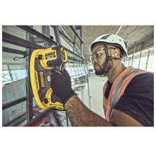 Un muncitor în construcții folosește un dispozitiv de ridicat sticlă DeWalt pe un șantier pentru a instala o fereastră.