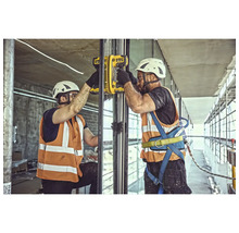 Doi muncitori în construcții montează un panou de sticlă cu o unealtă de montaj galbenă.