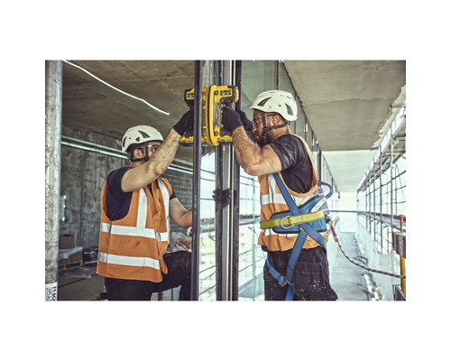 Doi muncitori în construcții montează un panou de sticlă cu o unealtă de montaj galbenă.