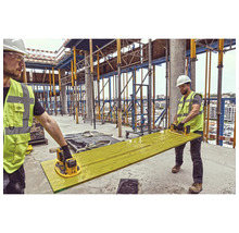 Doi muncitori în construcții șlefuiesc o scândură cu o șlefuitoare excentrică pe un șantier.