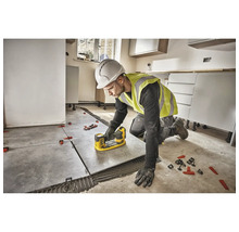 Un meșter montează gresie cu un sistem de nivelare a plăcilor într-o cameră.