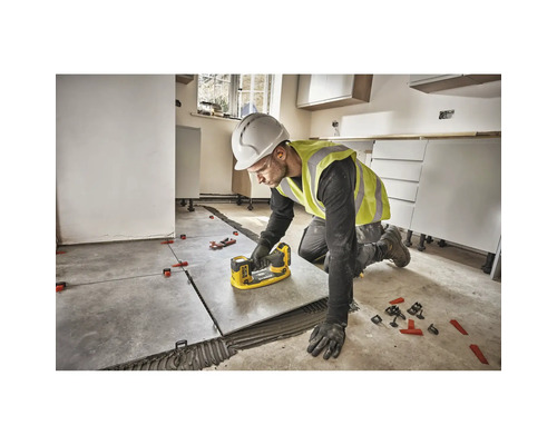 Un meșter montează gresie cu un sistem de nivelare a plăcilor într-o cameră.