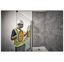 Un muncitor în construcții folosește un detector într-o baie pentru a localiza obiecte.