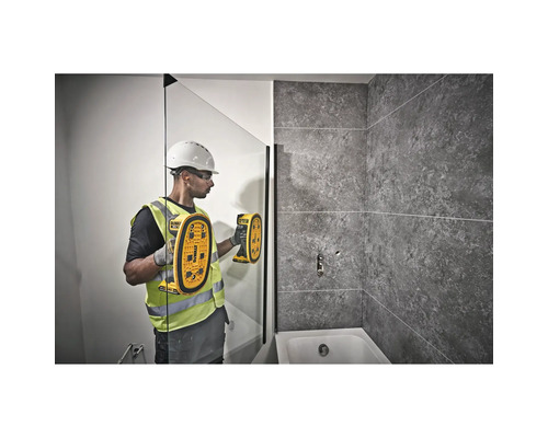 Un muncitor în construcții folosește un detector într-o baie pentru a localiza obiecte.