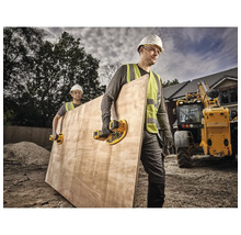 Doi muncitori în construcții care transportă o placă de lemn cu elevatoare cu ventuză pe un șantier.