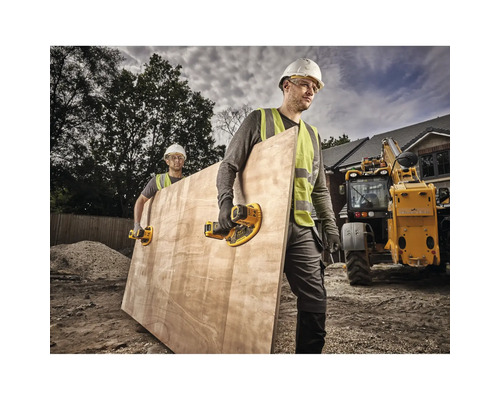 Doi muncitori în construcții care transportă o placă de lemn cu elevatoare cu ventuză pe un șantier.