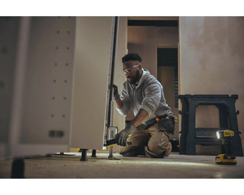 Meșter reglează dulapul de bucătărie cu instrument de nivelare într-un mediu luminos.