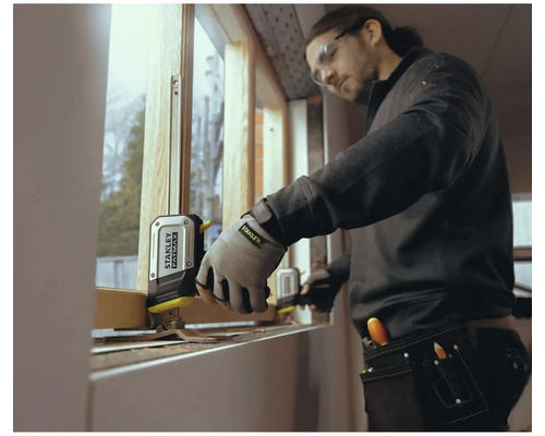 Artizan măsoară fereastra cu o ruletă Stanley Fatmax