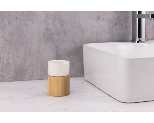 Pahar pentru periuțe de dinți din ceramică și bambus lângă o chiuvetă