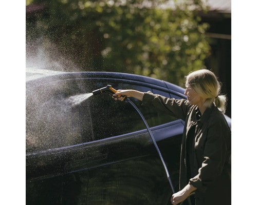 Femeie curăță mașina cu furtun de grădină și pistol de pulverizare