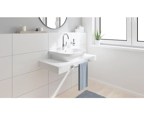 Baie modernă cu lavoar, baterie și suport pentru prosop pe un perete alb cu faianță