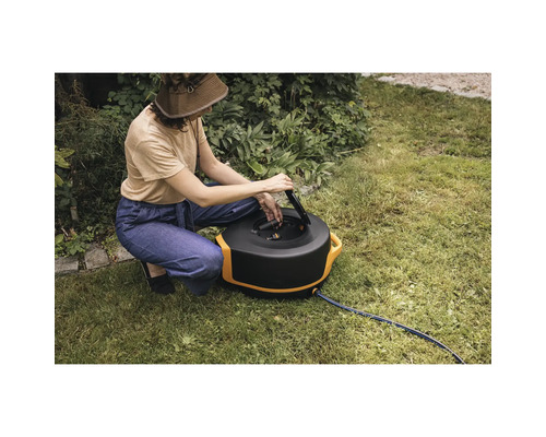 Femeie operând cutia de furtun în grădină