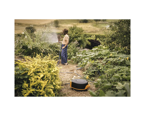 Irigarea grădinii cu tambur pentru furtun și persoană în grădină