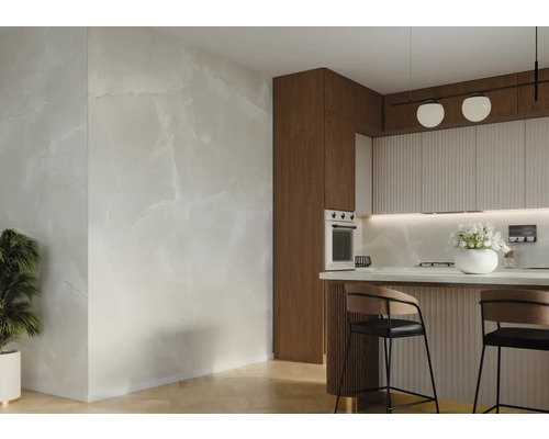 Spațiu luminos de bucătărie cu plăci de perete cu aspect de marmură, blat de bucătărie cu scaune de bar și decorațiuni