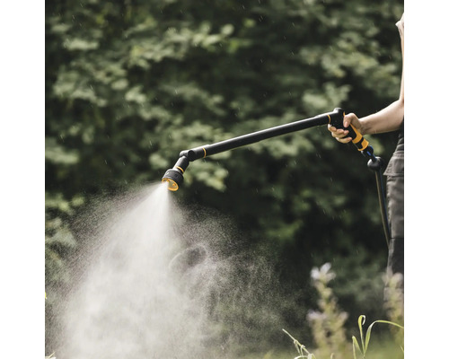O persoană ține un pulverizator de grădină pentru a uda plantele.