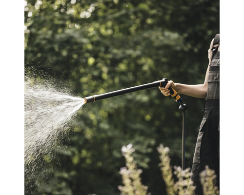 O persoană folosește un aspersor de grădină pentru a uda plantele.