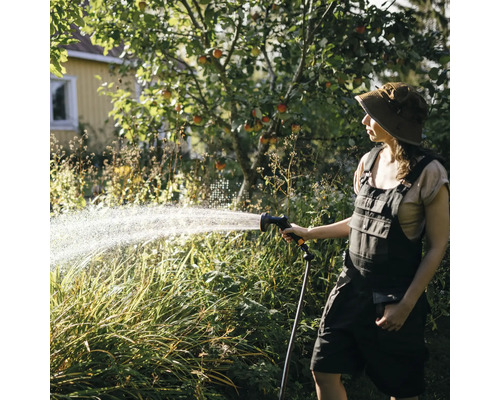 O femeie udă grădina cu un furtun de grădină