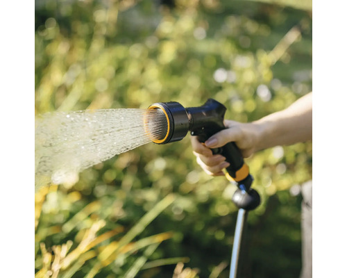 O persoană ține un furtun de grădină cu pistol de pulverizare din care iese apă.