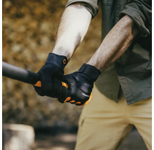 Un bărbat ține o unealtă cu mănuși de grădină negre marca Fiskars.