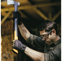 Bărbat cu ochelari de protecție și mănuși ține un topor de despicat Fiskars.