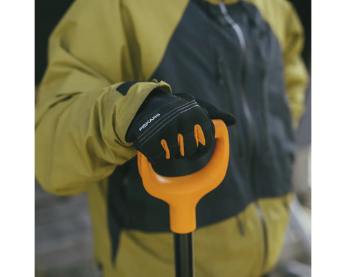 O persoană ține o lopată cu mănuși marca Fiskars.