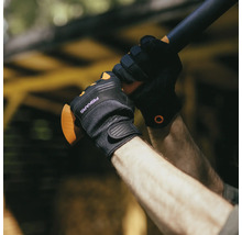 Persoană cu mănuși de lucru Fiskars ținând un mâner de topor