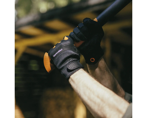Persoană cu mănuși de lucru Fiskars ținând un mâner de topor
