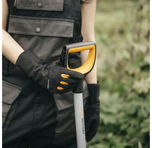 O persoană cu mănuși ține un hârleț Fiskars.