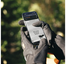 O persoană cu mănuși de grădinărit se uită la site-ul web Fiskars pe un smartphone.