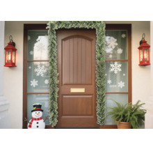 Ușă de intrare decorată cu ghirlandă de brad, autocolante cu fulgi de zăpadă și felinare