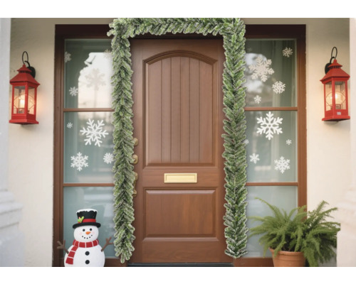 Ușă de intrare decorată cu ghirlandă de brad, autocolante cu fulgi de zăpadă și felinare