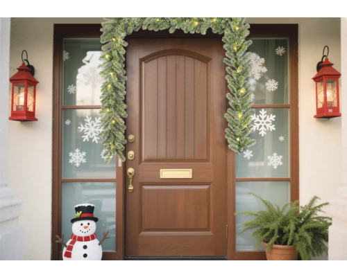 Ușă de intrare decorată cu ghirlandă, felinare, autocolante cu fulgi de zăpadă și om de zăpadă