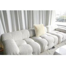 Canapea modulară cu pernă și structură tapițată în fața unei ferestre cu perdea