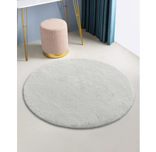 Covor rotund de culoare deschisă într-o cameră cu un taburet și o masă.