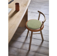 Scaun din lemn cu pernă rotundă și spătar lângă o masă.