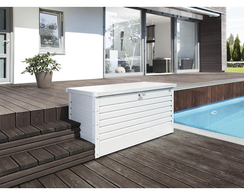 Fotografie cu o cutie de depozitare metalică albă pe o terasă lângă o piscină.