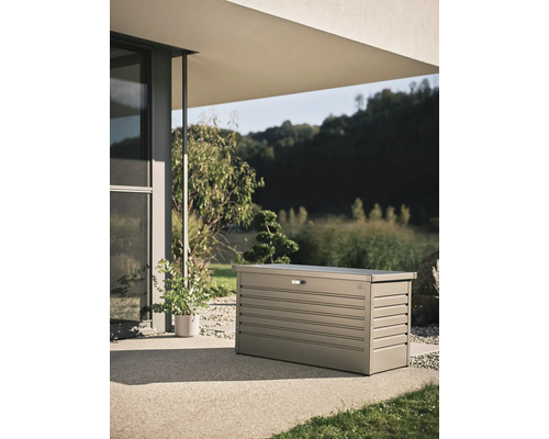 Cufăr de grădină din metal pe o terasă în fața unei case moderne