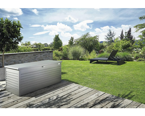 Peisaj de grădină cu o cutie de depozitare metalică și un șezlong pe un gazon