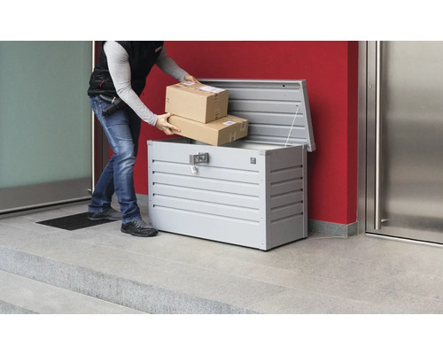 Curier care pune colete într-o cutie poștală metalică pentru colete