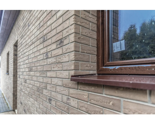 Exteriorul unei case cu fațadă din cărămidă aparentă și o fereastră