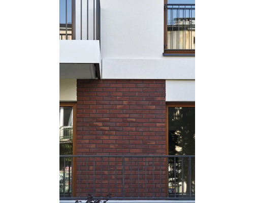 Fațada unei clădiri cu zidărie din cărămidă roșie și balcoane