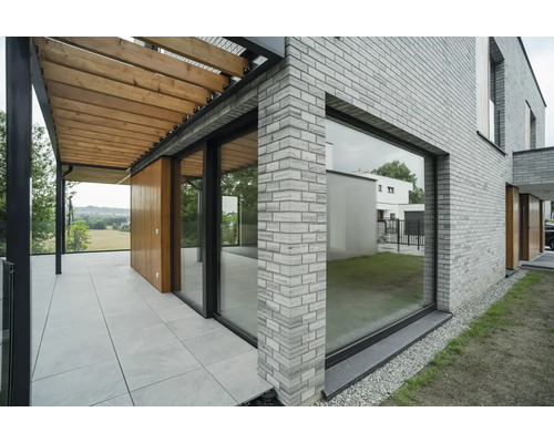 Vedere exterioară a unei case cu zidărie de cărămidă, terasă şi pergolă