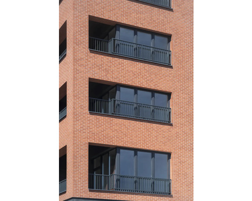 Fațada unei clădiri rezidențiale cu balcoane și zidărie din cărămidă