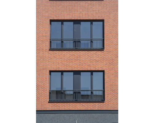 Fațadă de casă cu zidărie de cărămidă și ferestre cu balustradă