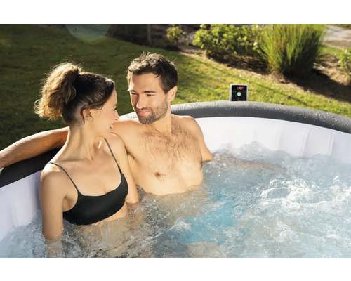 Un cuplu se relaxează într-un jacuzzi gonflabil în grădină.