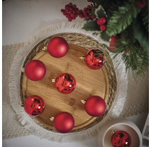 Aranjament decorativ de globuri roșii de Crăciun pe o tavă de lemn