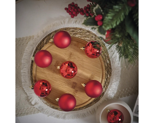 Aranjament decorativ de globuri roșii de Crăciun pe o tavă de lemn