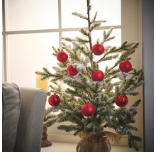 Brad mic de Crăciun decorat cu globuri roșii într-un sac de iută