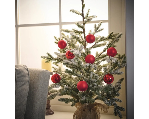 Brad mic de Crăciun decorat cu globuri roșii într-un sac de iută