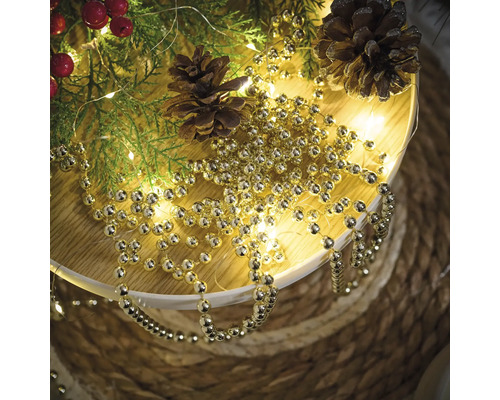 Decorație cu ramuri de brad, conuri de pin și ghirlandă aurie cu bile